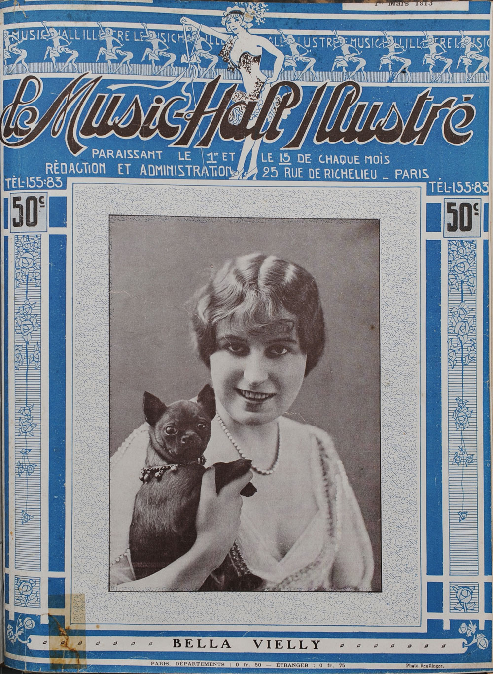 A young woman with light skin and short, dark hair holds a small dog. The woman is smiling at the camera. She wears a strand of pearls and a sheer top with elabororate decorations. The dog has dark fur and pricked ears. It is wearing a scarf with bells. The photo appears on the cover of a magazine about cabaret entertainment.