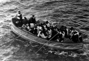 A rowboat is filled with passengers in life vests.